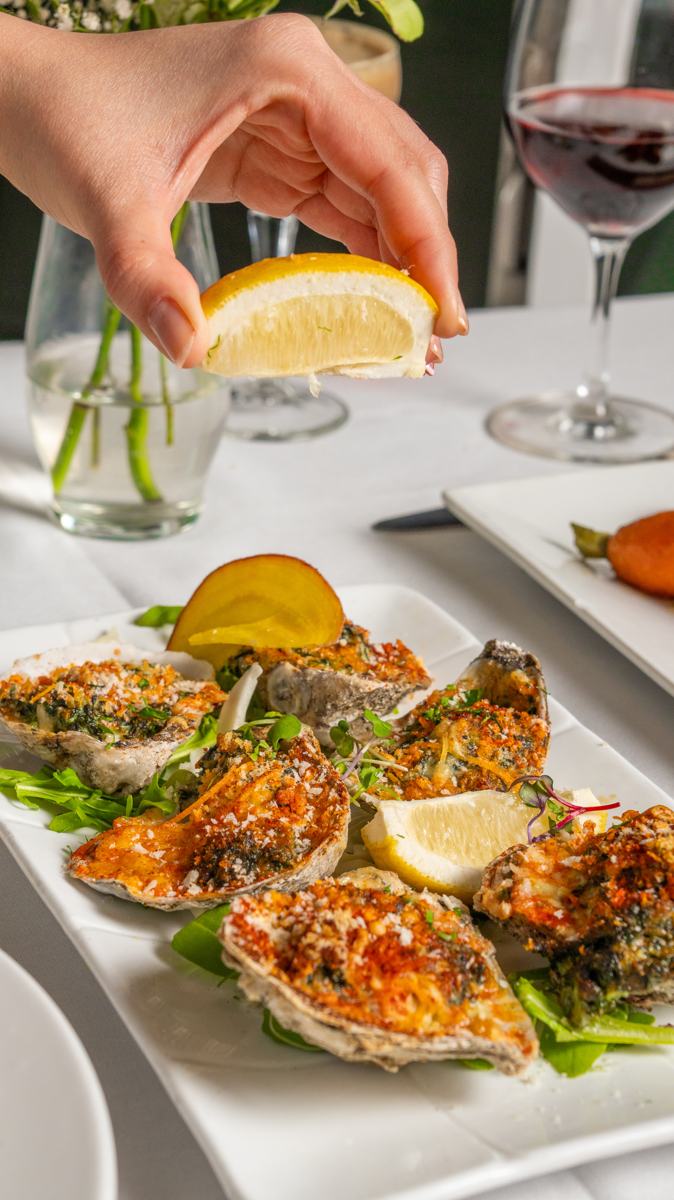 A guest squeezing lemon over oysters